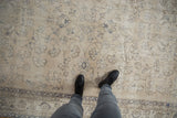 Distressed Sparta carpet with faded ivory, dusty blue vinery, wear, and boots.