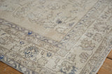Close-up of vintage distressed Turkish Sparta rug: ivory field, faded blue vinery, worn pile.
