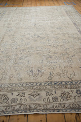 Close-up of distressed Sparta carpet, showing worn ivory field with faded blue curvilinear pattern.
