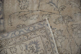 Distressed vintage Sparta carpet corner with worn ivory pile, exposed foundation, and fringe.