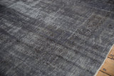 Worn pile on the overdyed Oushak carpet shows the charcoal and ivory hand-knotted texture.