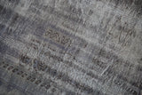 Worn texture and exposed knot heads of a distressed charcoal and ivory overdyed rug.