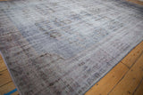 Vintage distressed Oushak carpet with worn texture, foundation showing, dusty blue and mauve hues.