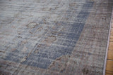 Vintage distressed Oushak carpet with worn texture, exposed foundation, dusty blue, and mauve.