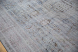 Distressed Oushak rug texture with foundation showing, muted denim blue and mauve tones.