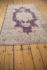 Distressed vintage Sparta rug's bottom border, fringe, and worn aubergine and ivory pile.