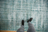 Distressed vintage Oushak carpet with worn texture in pale turquoise, ivory, and charcoal.