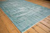 Corner view of the vintage distressed Oushak carpet with dusty turquoise, ivory pile, and short fringe.