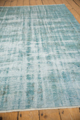 Angled close-up of distressed vintage Oushak pile, showing pale turquoise, ivory, and charcoal wear.