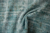 Textural fold of distressed Oushak carpet showing worn knot heads in dusty turquoise and ivory.