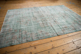 Distressed Oushak carpet corner with worn jade green and brown scrolling vines.
