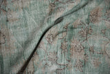 Distressed vintage Oushak carpet pile showing worn jade green, ivory, and brown tones.