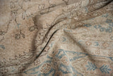 Distressed texture of vintage Sparta carpet, showing faded vinery, pale teal, and coffee brown tones.