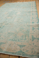 Distressed Oushak carpet in pale turquoise, ivory, sand, with worn knot heads and faint foundation showing.
