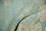 Textured pile of a distressed vintage Oushak rug, featuring pale turquoise and sand patterns.