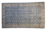 Distressed Turkish Sparta rug with faded denim blue lattice and floral pattern on antique ivory.