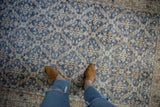Distressed vintage Sparta rug with dusty denim blue, ivory lattice floral design, foundation showing.