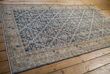 Distressed Sparta rug corner showing intact side selvage, blue, ivory lattice, and knot wear.
