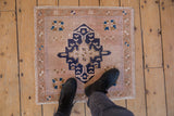 Distressed vintage Oushak rug texture with pale blush, navy, and beige geometric florals.