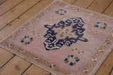 Distressed vintage Oushak square rug with pale blush field and navy geometric medallion.