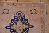 Distressed vintage Oushak rug showing navy blue geometric medallion fragment and starburst motifs.
