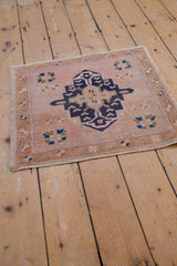 Distressed Oushak rug's navy geometric medallion, pale blush field, starburst florals, even wear.
