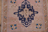 Distressed pale blush pile with navy geometric motif and brown patterned side border.