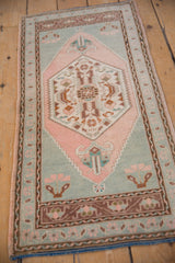 Distressed Oushak rug's hexagonal medallion, with floral blossoms in blush, seafoam green, and coffee.