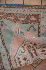 Distressed vintage Oushak rug detail with textured blush, seafoam green, and brown floral motifs.