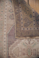 Folded vintage distressed Oushak rug revealing abrashed ivory pile, reverse, and selvage.