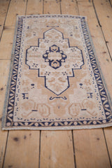 Vintage distressed Oushak runner's meandering vine border and time-softened beige, cobalt hues.