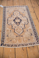 Distressed Oushak rug showing shield medallion, starburst florals, and cobalt blue vine border.