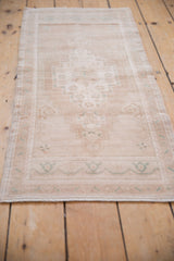 Angled close-up of distressed Oushak rug side, with intact selvage and soft ivory, beige, seafoam green colors.