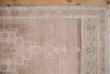 Distressed Oushak rug close-up showing worn texture, stepped motifs in beige and seafoam green.