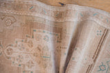 Distressed Oushak rug pile with soft folds and faded ivory, beige, seafoam motifs.