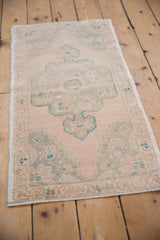 Distressed ivory and seafoam green pile with visible knot heads and intact selvage.