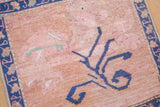 Abrashed blush field with bold cobalt blue floral stem motif on vintage Oushak.