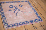 Distressed Oushak rug corner showing wear, cobalt blue floral border, and abrashed deep beige field.