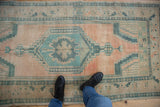 Distressed Oushak rug runner with worn cantaloupe melon field and seafoam green geometric motifs.