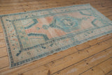 Distressed Oushak runner's abrashed cantaloupe field, seafoam green floral border, and corner spandrel.