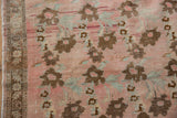 Vintage distressed Oushak runner's blush field, worn bronze floral motifs, and patterned side border.