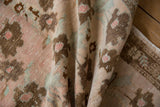 Distressed Oushak rug pile, showing worn dusty blush, bronze floral motifs and faint foundation.