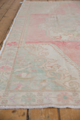 Side angle of a distressed Oushak runner showing its worn texture in pink and seafoam green.