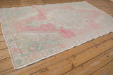 Angled view down the length of a distressed Oushak runner in soft pink and seafoam green.