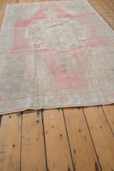 Low angle on the vintage Oushak rug's restored side cord selvage and worn, low pile.