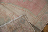 Corner of a vintage Oushak runner folded to show its hand-knotted back and worn pile.