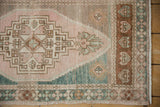 Faded beige, deep green, pink geometric lightning stepped spandrel on distressed Oushak rug.