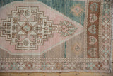 Distressed Oushak rug corner detail, showing geometric spandrel in beige, pink, and muted green.