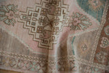 Distressed Oushak rug: geometric floral pattern, worn knot heads, beige, green, bronze.