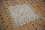 Distressed Oushak rug showing intact side cord selvage and soft beige, green floral detail.